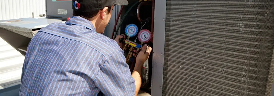 HVAC technician servicing a condenser unit in Olympia